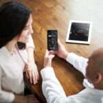 HVAC tech showing homeowner how to control their lennox smart thermostat on a phone