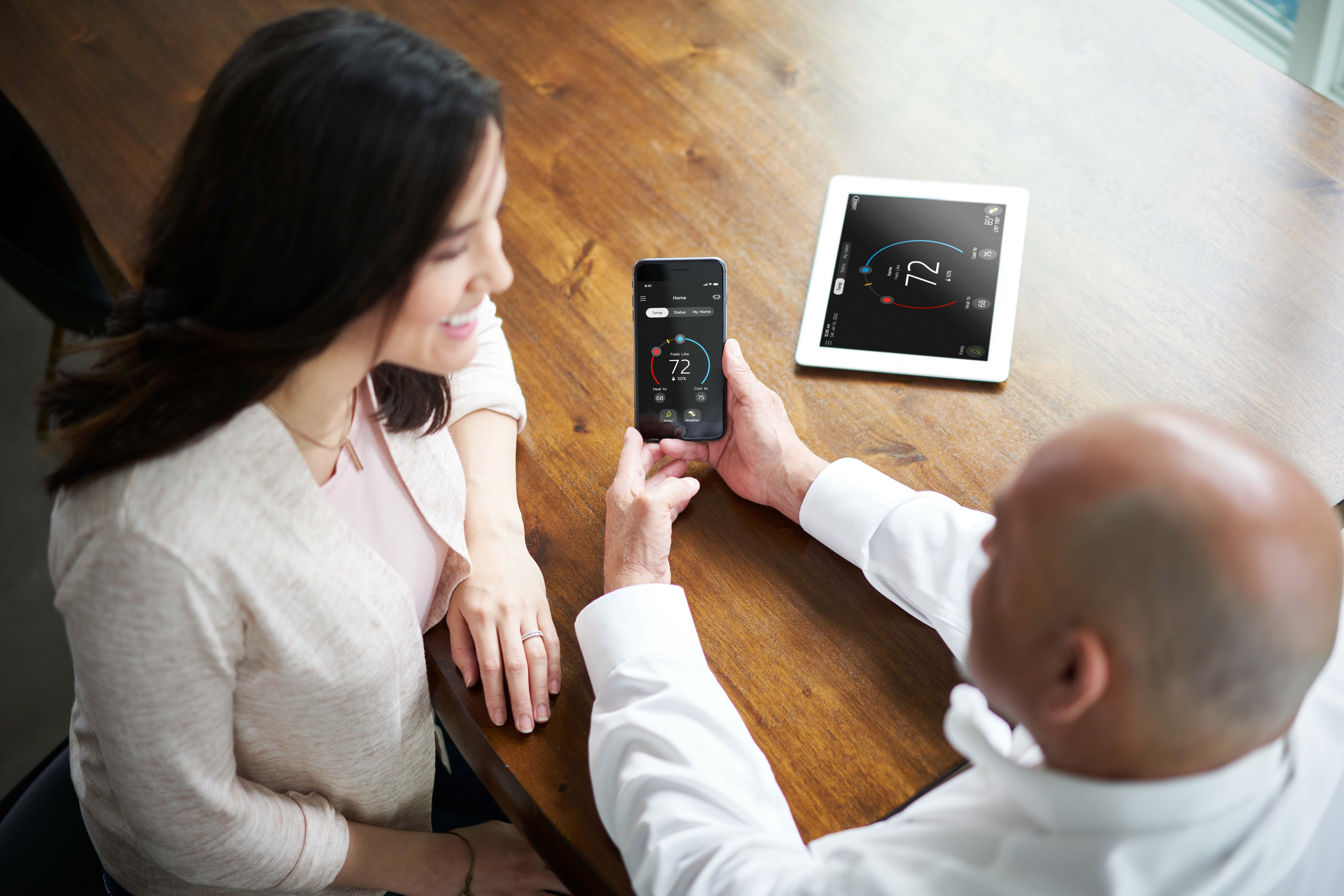 HVAC tech showing homeowner how to control their lennox smart thermostat on a phone